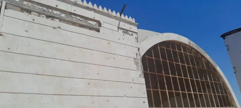 Bullet holes across the masjid's stone wall