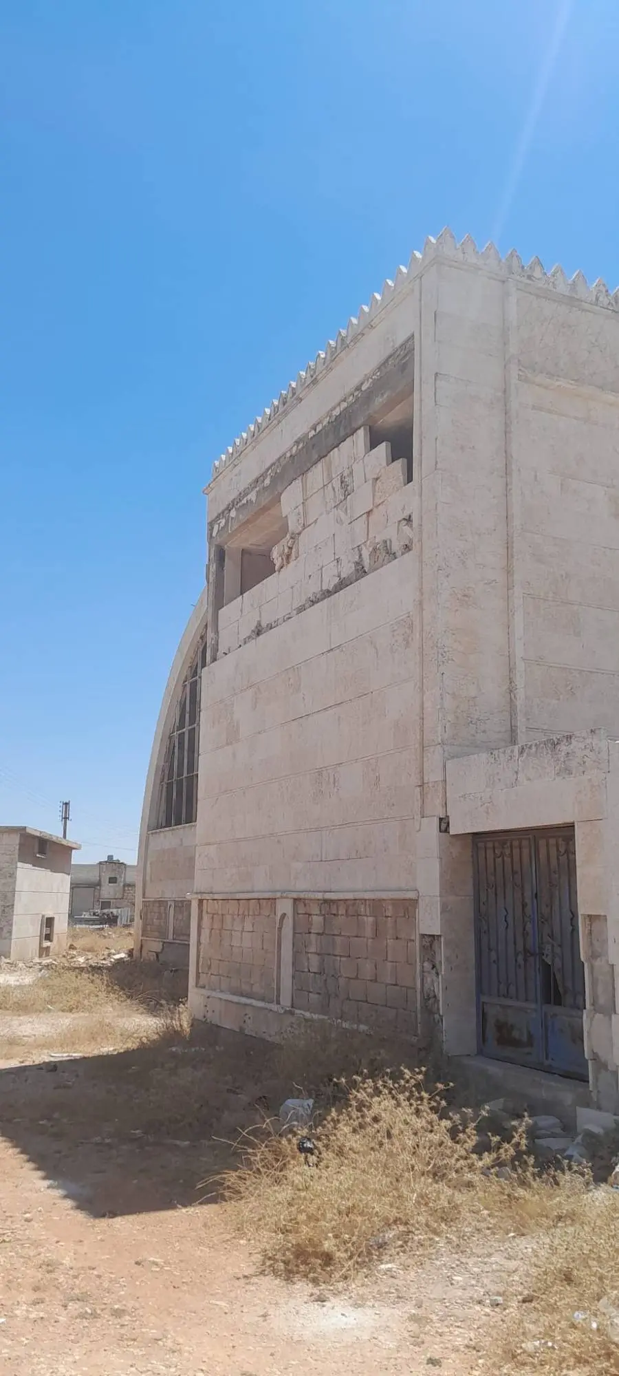 Stone cladding torn from the corner of the masjid, exposing the structure beneath