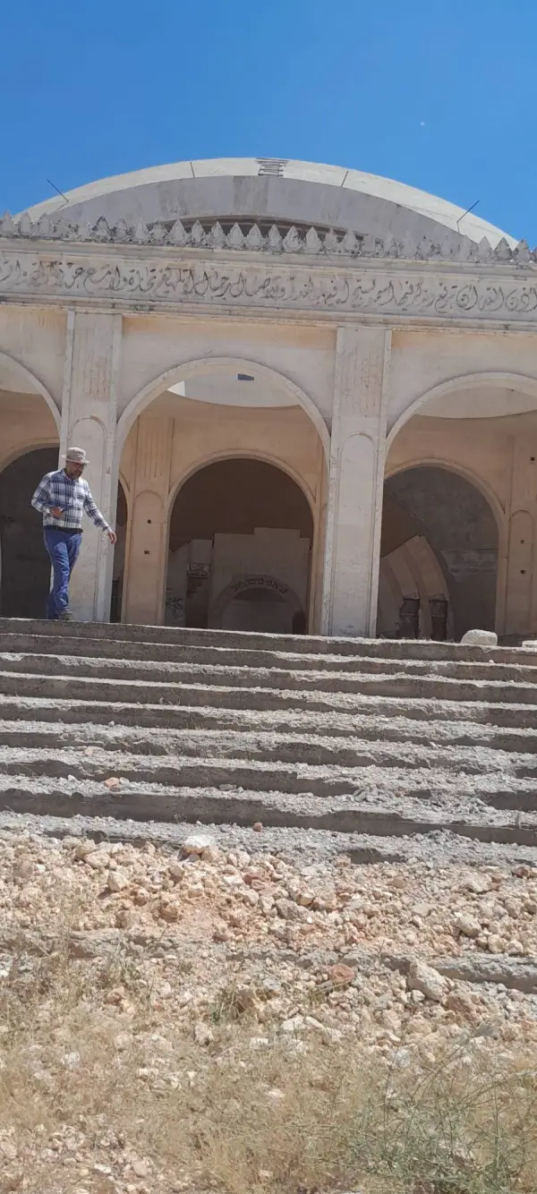 A visitor descending the broken entrance stairs beneath the dome