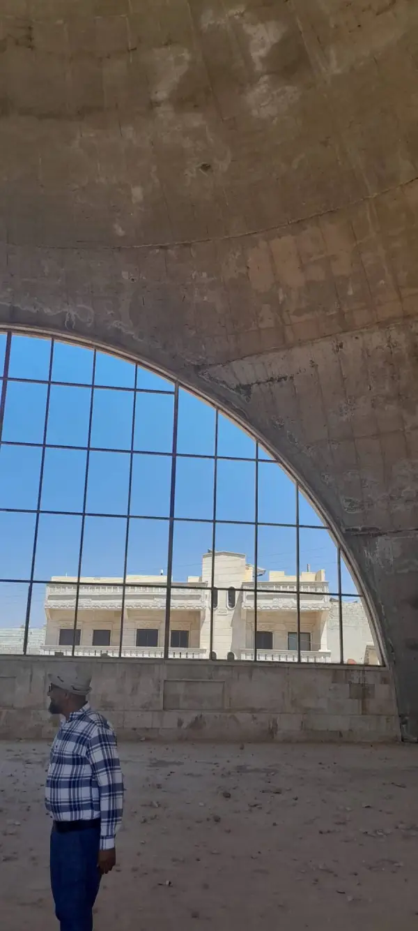 A visitor beneath the bare concrete dome and arched window